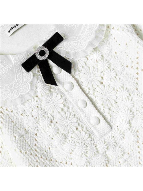 Abito Ideale per quando una persona fortunata si sente particolarmente femminile, questo abito bianco in maglia traforata è impreziosito da bordi in pizzo floreale e da un bavaglino decorato con fiocco. Aggiungi il nostro cerchietto scintillante per un tocco di fascino in più.Stile aderenteQuesto stile ha un allungamento minimoChiusura con bottoni sul davantiBavaglino smerlato e dettaglio del colletto in pizzoSpilla a fiocco rimovibile SELF PORTRAIT | AW25-728S-WWHITE